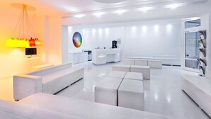 A modern, minimalist living room with white sofas and a central coffee table.