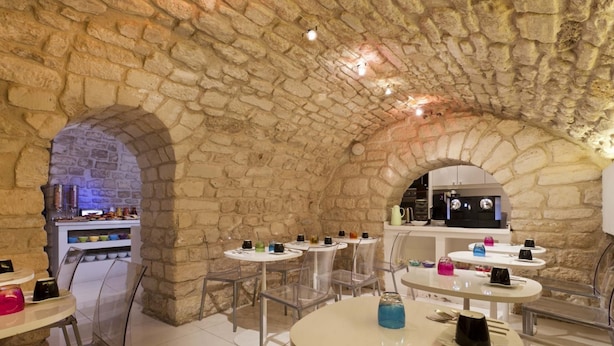 A restaurant with stone arches, round tables, and clear chairs.