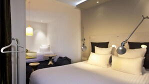 A hotel room with a large bed, bedside lamps, a small round table, and a hanging light fixture.