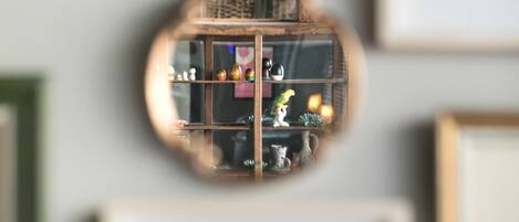 A mirror reflecting a room with framed pictures and a vase with flowers.