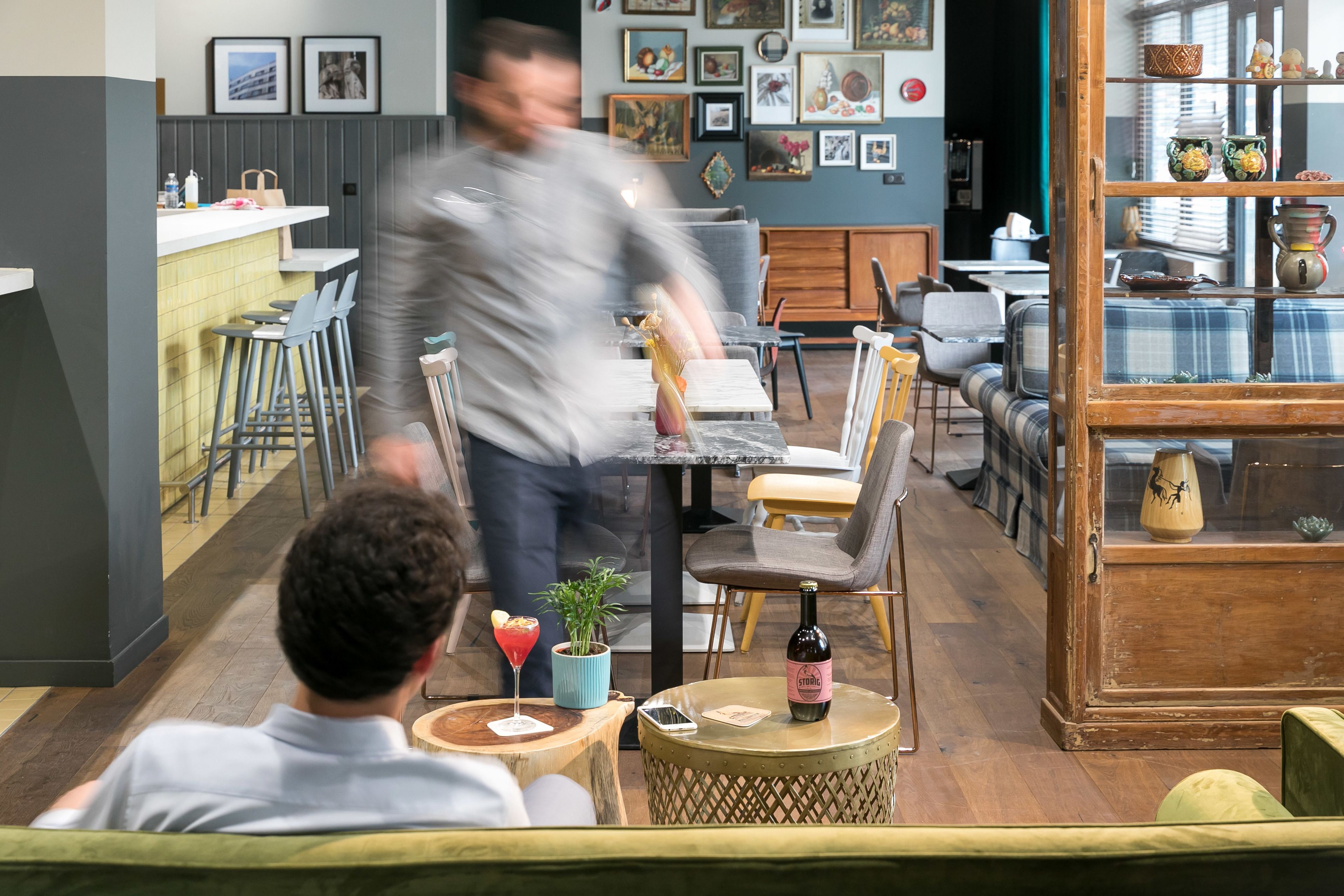 Een restaurant met een bar, houten meubels en diverse decoratieve objecten aan de muren.