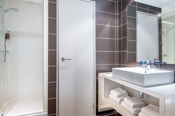 A modern bathroom with a shower, a sink, and a towel rack. - Hotel Kaijoo by HappyCulture (Strasbourg)