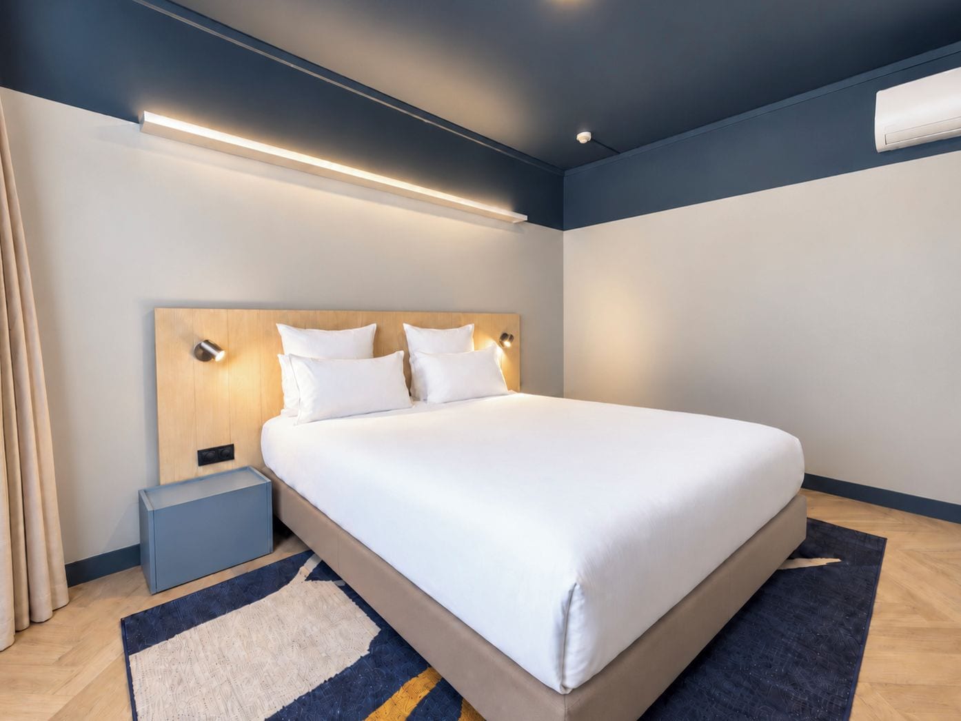 Une chambre d’hôtel moderne avec un grand lit, des tables de chevet et un luminaire au plafond.