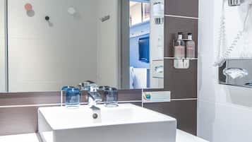Une salle de bain moderne avec un grand miroir, un lavabo blanc et un porte-serviettes.