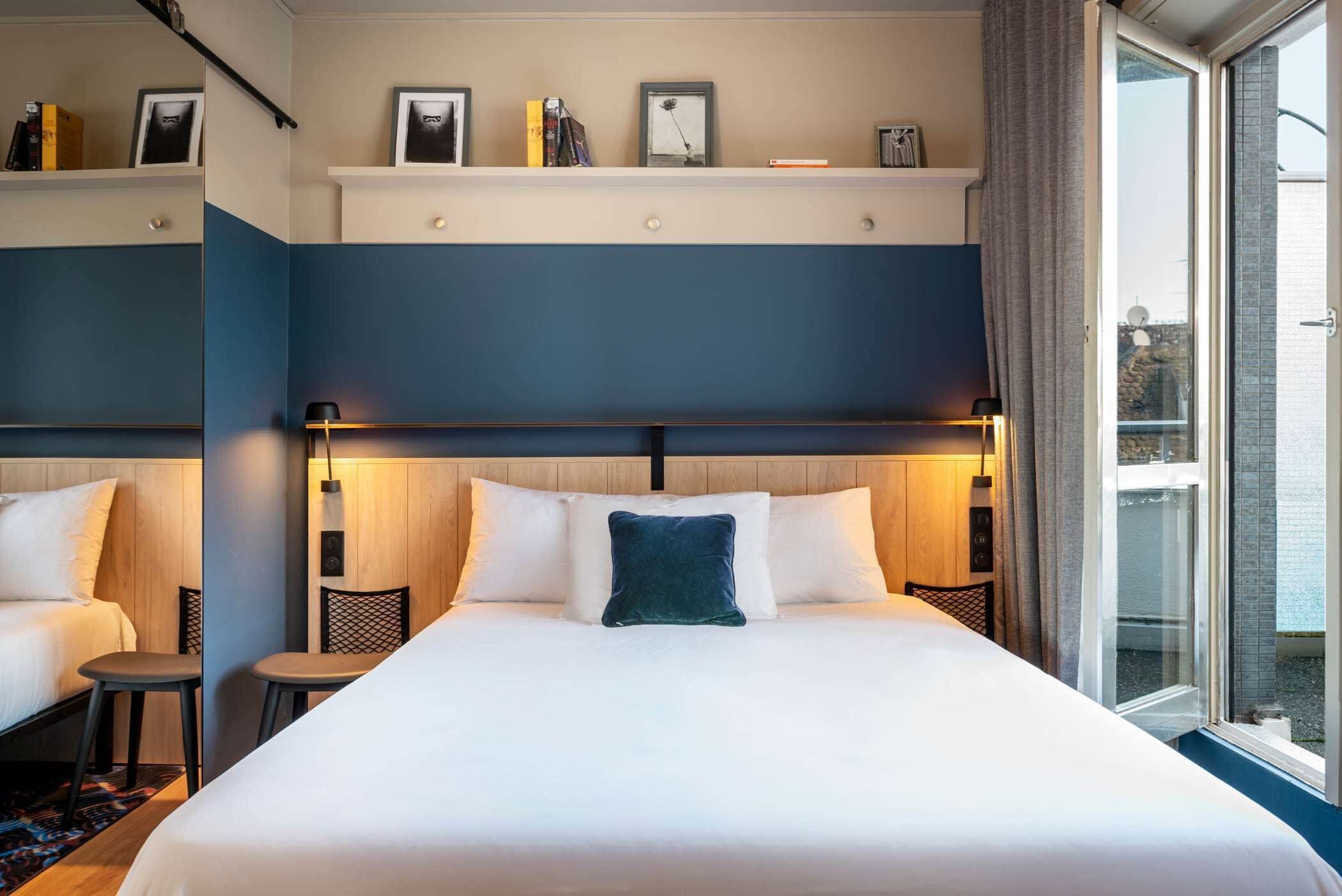 A hotel room with a large bed, two bedside tables, a small seating area, and a window with a view.