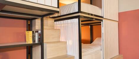 A bunk bed room with a wooden ladder, a shelf with books, and a curtain.