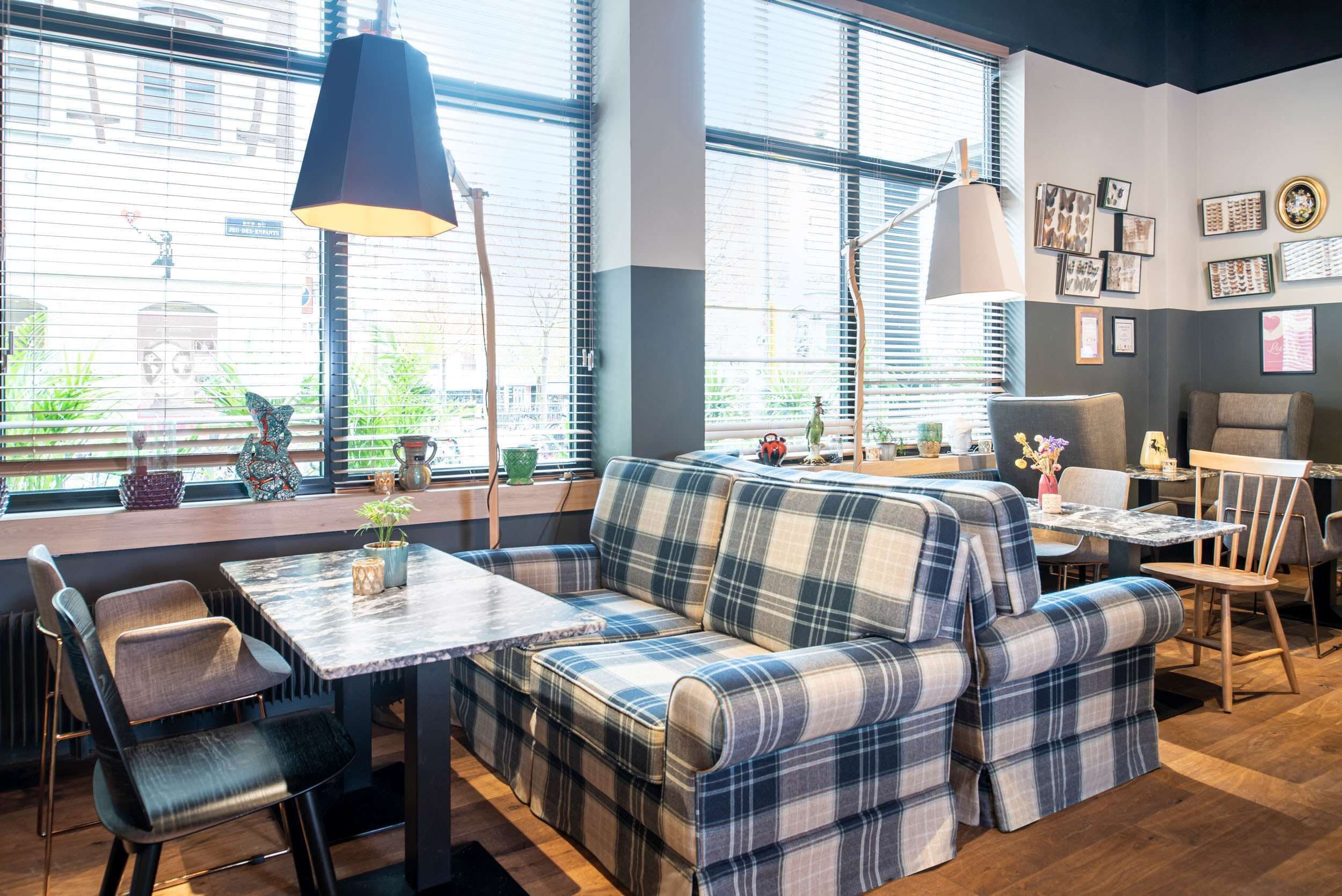 Un interior moderno con un sofá, sillas, una mesa y un ventanal con persianas.