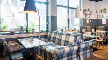 Un interior moderno con un sofá, sillas, una mesa y un ventanal con persianas.