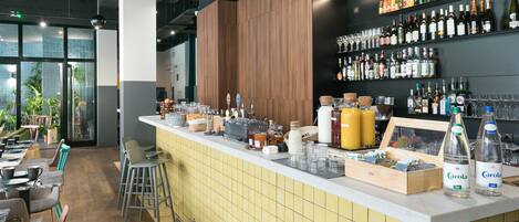 Uma área de bar com balcão revestido de azulejos, diversos garrafas, copos e parede de painel de madeira.