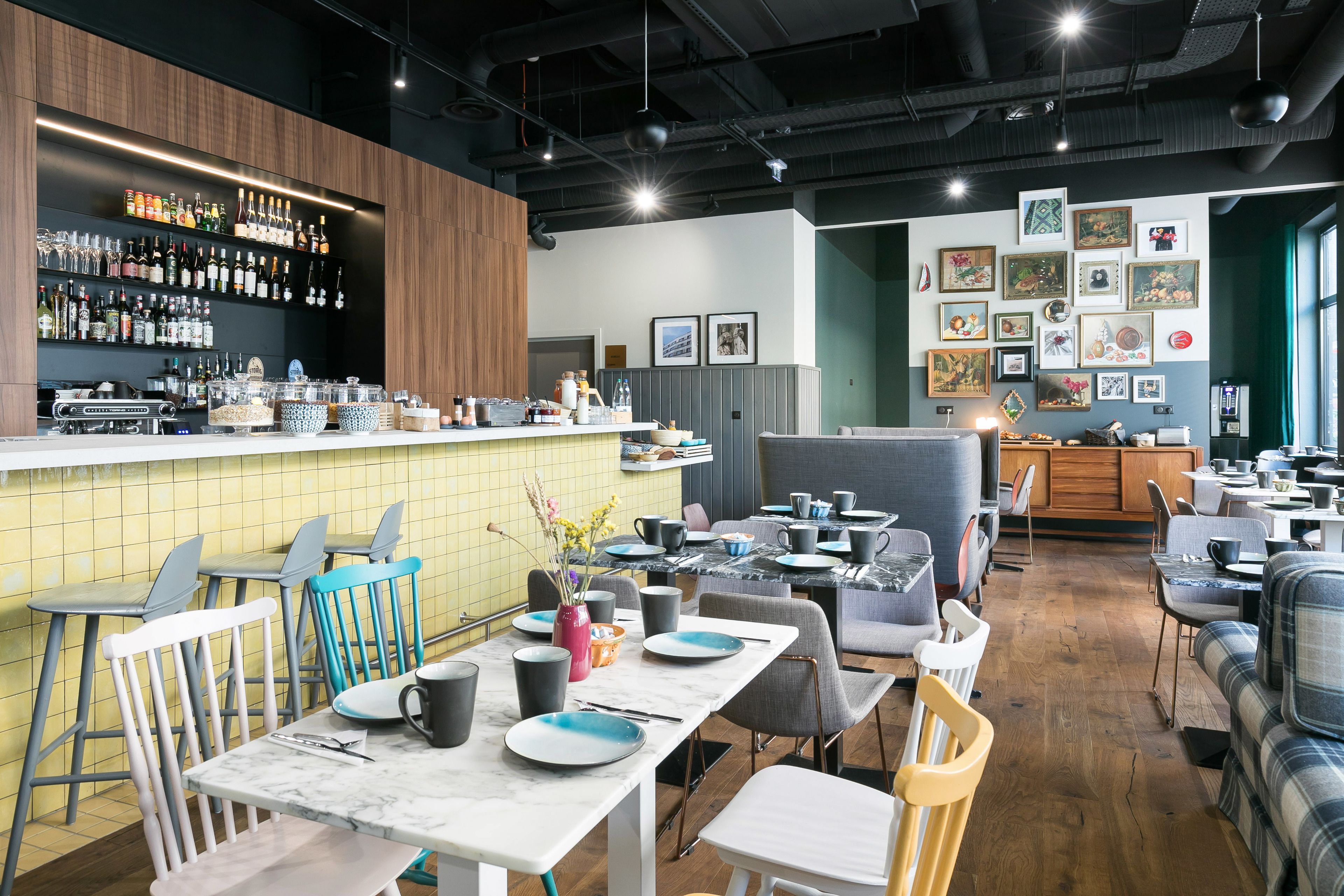 A modern restaurant with a bar area, wooden bar counter, and various seating options including tables and chairs.