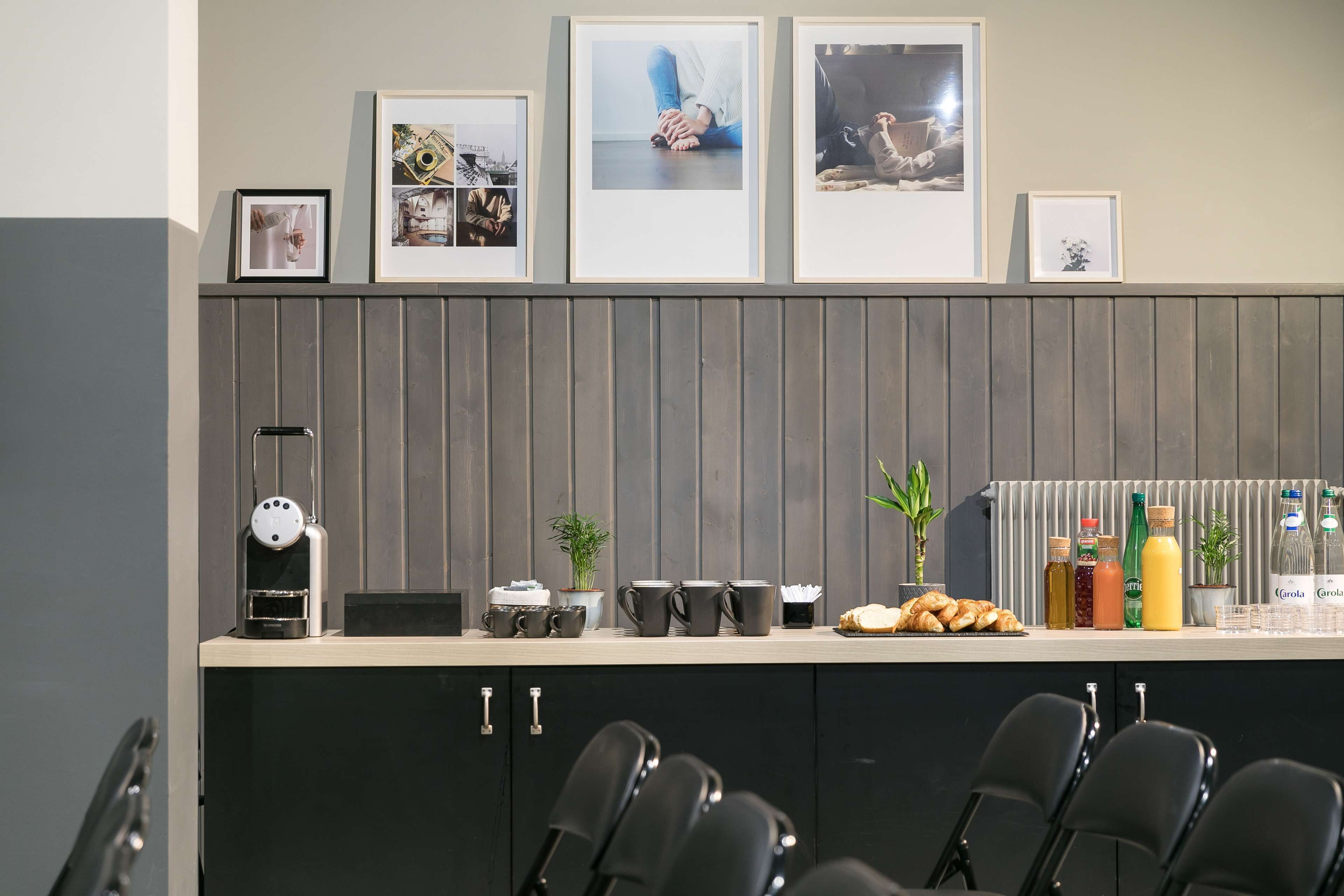 A modern kitchen with a wooden panel backsplash, a coffee machine, and a breakfast bar with seating.