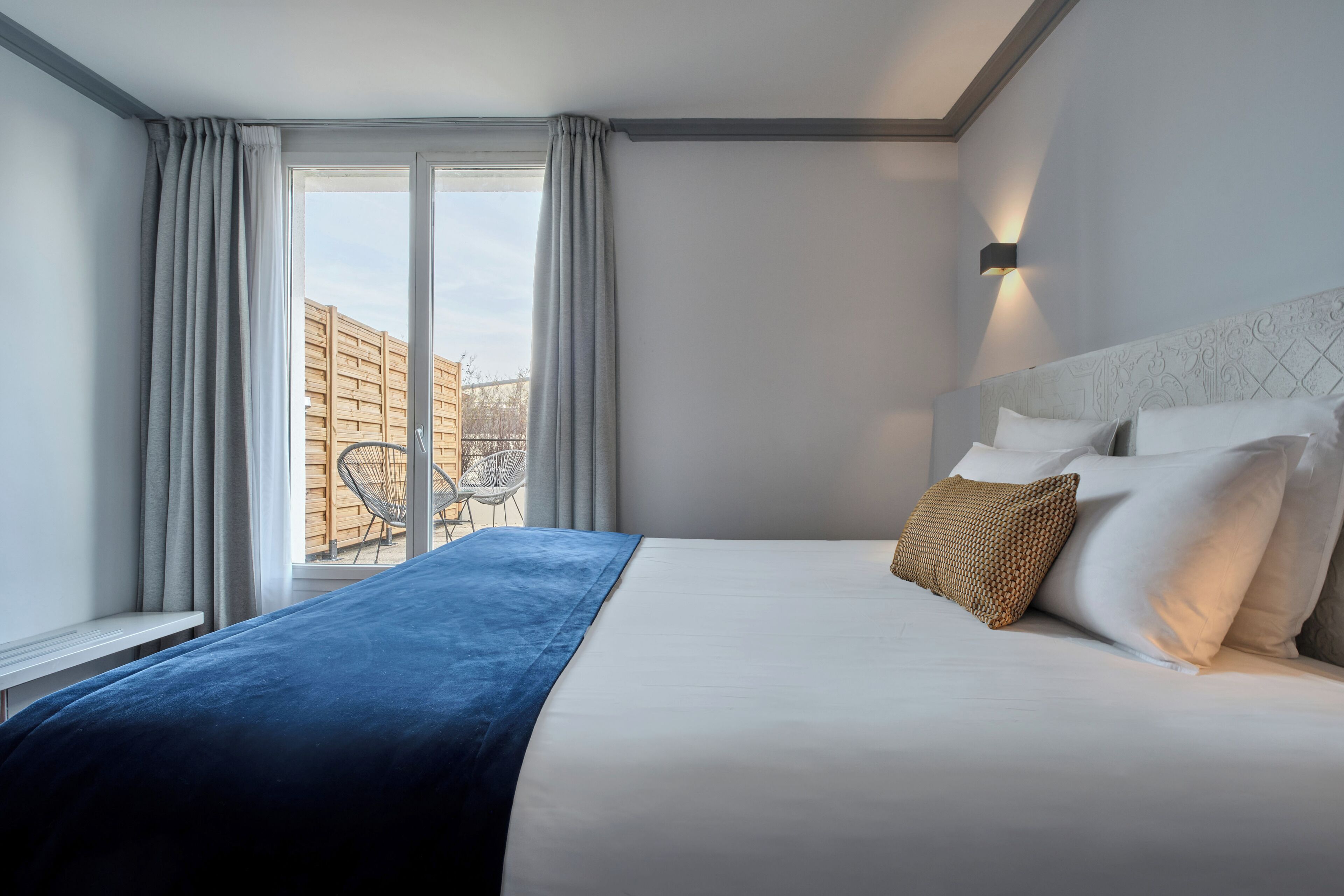 Quarto de hotel com uma cama grande, vista para o exterior e janela com cortinas.