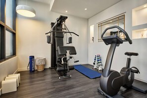 Une salle de sport équipée d’un vélo d’appartement, d’une machine de musculation et d’un tapis bleu.