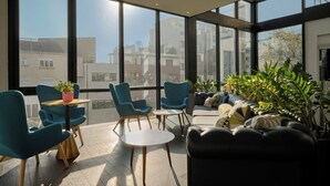 A modern interior with large windows, a sofa, chairs, and a small table. - Hotel Atrium by HappyCulture (Suresnes)