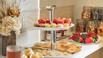 A buffet table with pastries, fruits, and jars of preserves.