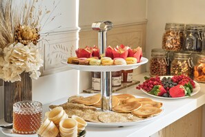 A buffet table with pastries, fruits, and jars of preserves.