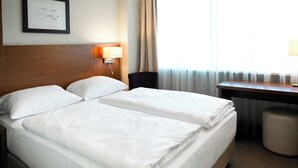 Een hotelkamer met twee bedden, een bureau, een stoel en een lamp.