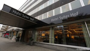 Een moderne hotelgevel met grote ramen en een opvallend entreebord.