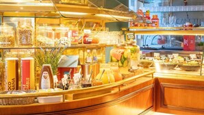 A well-lit café with a variety of food and drink options displayed in glass containers and jars. - Bernstein Villa Kastania (Berlin)