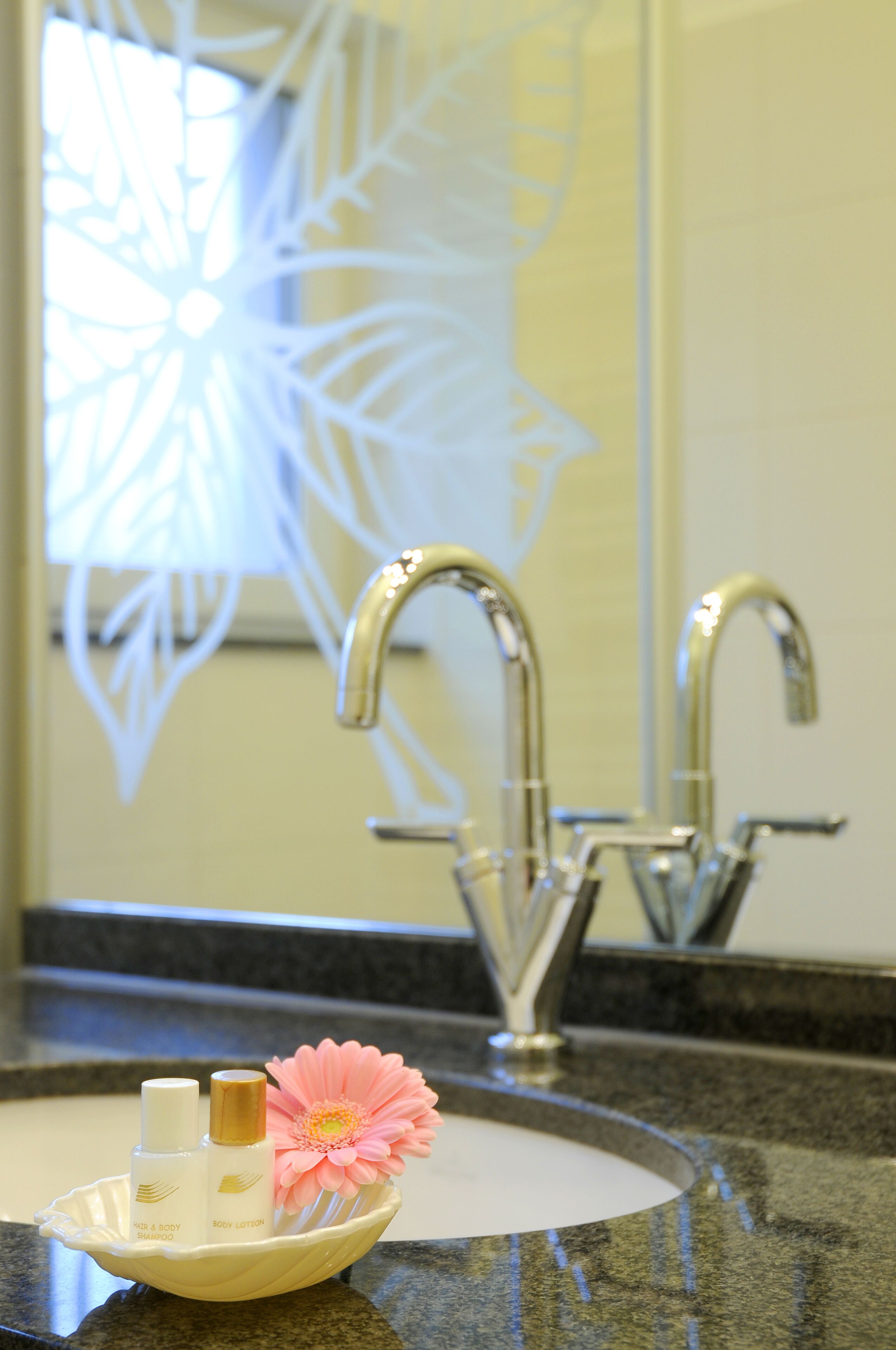 A bathroom sink with a decorative bowl containing toiletries and a flower.
