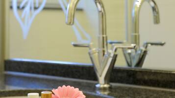 A bathroom sink with a decorative bowl containing toiletries and a flower.