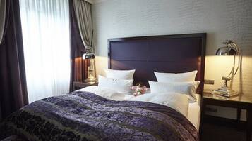 Una camera d'albergo con un letto grande, un comodino con una lampada e una finestra con tende.