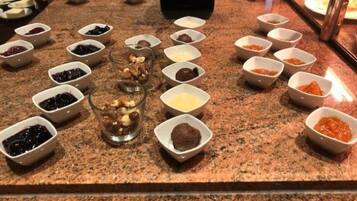 A buffet with various food items in small bowls, arranged on a granite countertop.