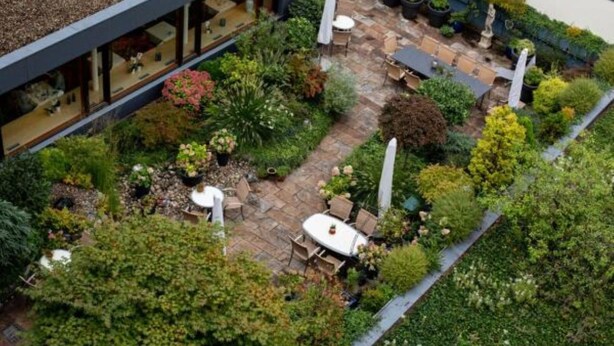 An aerial view of a rooftop garden with a patio area, seating, and potted plants. - Kronenhotel Stuttgart (Stuttgart)