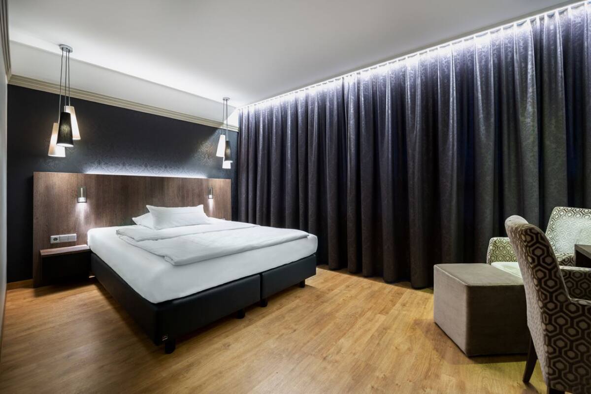 Une chambre d’hôtel moderne, dotée d’un grand lit, de tables de chevet, d’un bureau et d’une chaise.