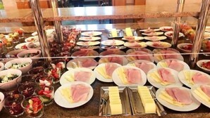 A buffet with various food items including plates of ham, cheese, and fruit. - Kronenhotel Stuttgart (Stuttgart)