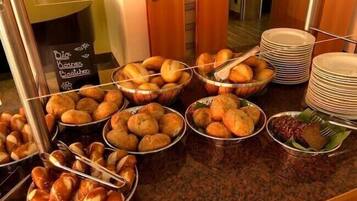 A buffet counter with various baked goods and dishes, including bread and pastries, displayed in baskets and on plates.