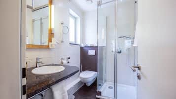 A modern bathroom with a glass-enclosed shower, a white sink, and a toilet.