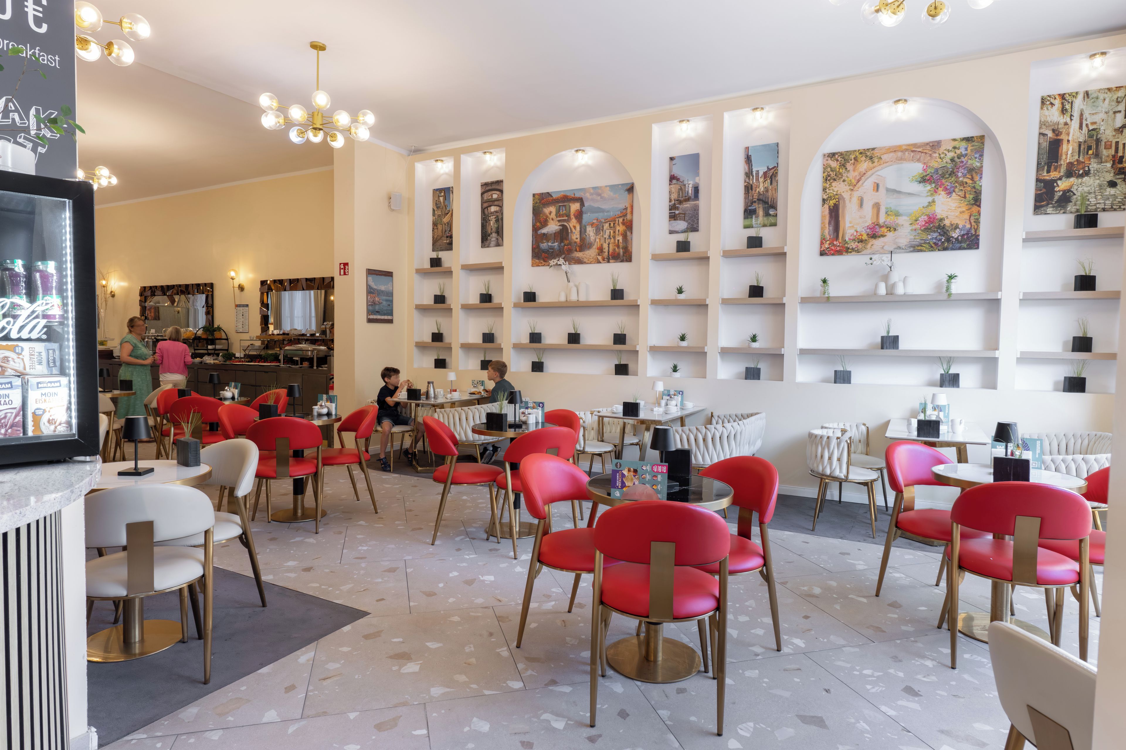 A restaurant with red chairs and tables, a bar area, and wall-mounted shelves with potted plants.