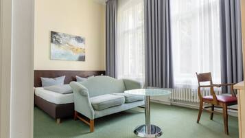 A hotel room with a bed, a sofa, a dining table, and a chair.