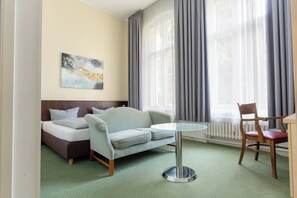 A hotel room with a bed, a sofa, a dining table, and a chair. - Hotel Tiergarten Berlin (Berlin)