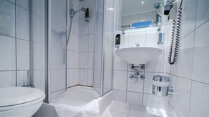 A modern bathroom with a toilet, a glass-enclosed shower, a sink, and a mirror.