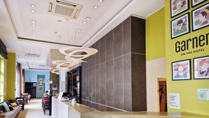 A hotel reception area with a modern design, featuring a reception desk, seating area, and a wall with framed artwork. - Garner Hotel Bochum by IHG (Bochum)