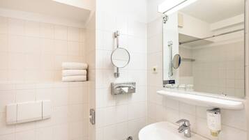 Un baño moderno con un lavamanos blanco, un espejo, un perchero y una zona de ducha.