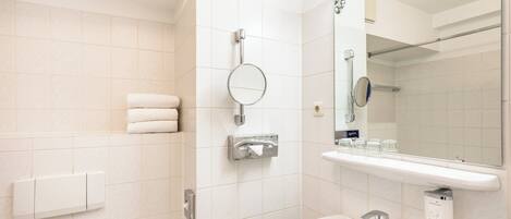 Un baño moderno con un lavamanos blanco, un espejo, un perchero y una zona de ducha.
