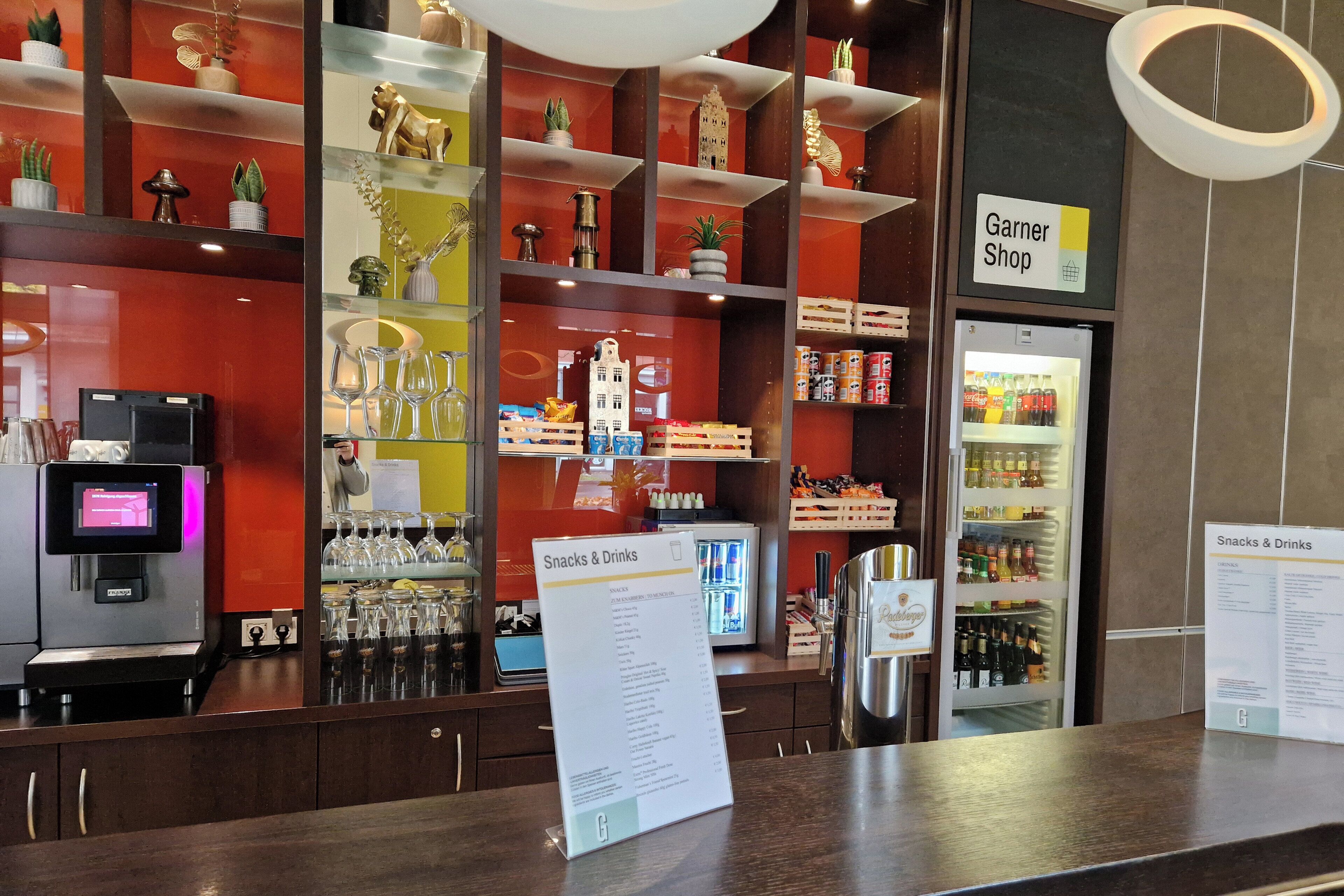 A counter with a menu sign, a Garner Shop sign, and a refrigerated display of snacks and drinks.