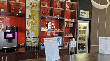 A counter with a menu sign, a Garner Shop sign, and a refrigerated display of snacks and drinks.