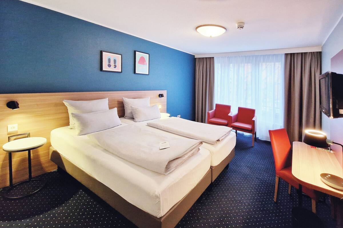 Een hotelkamer met twee bedden, een bureau, een stoel en een televisie.