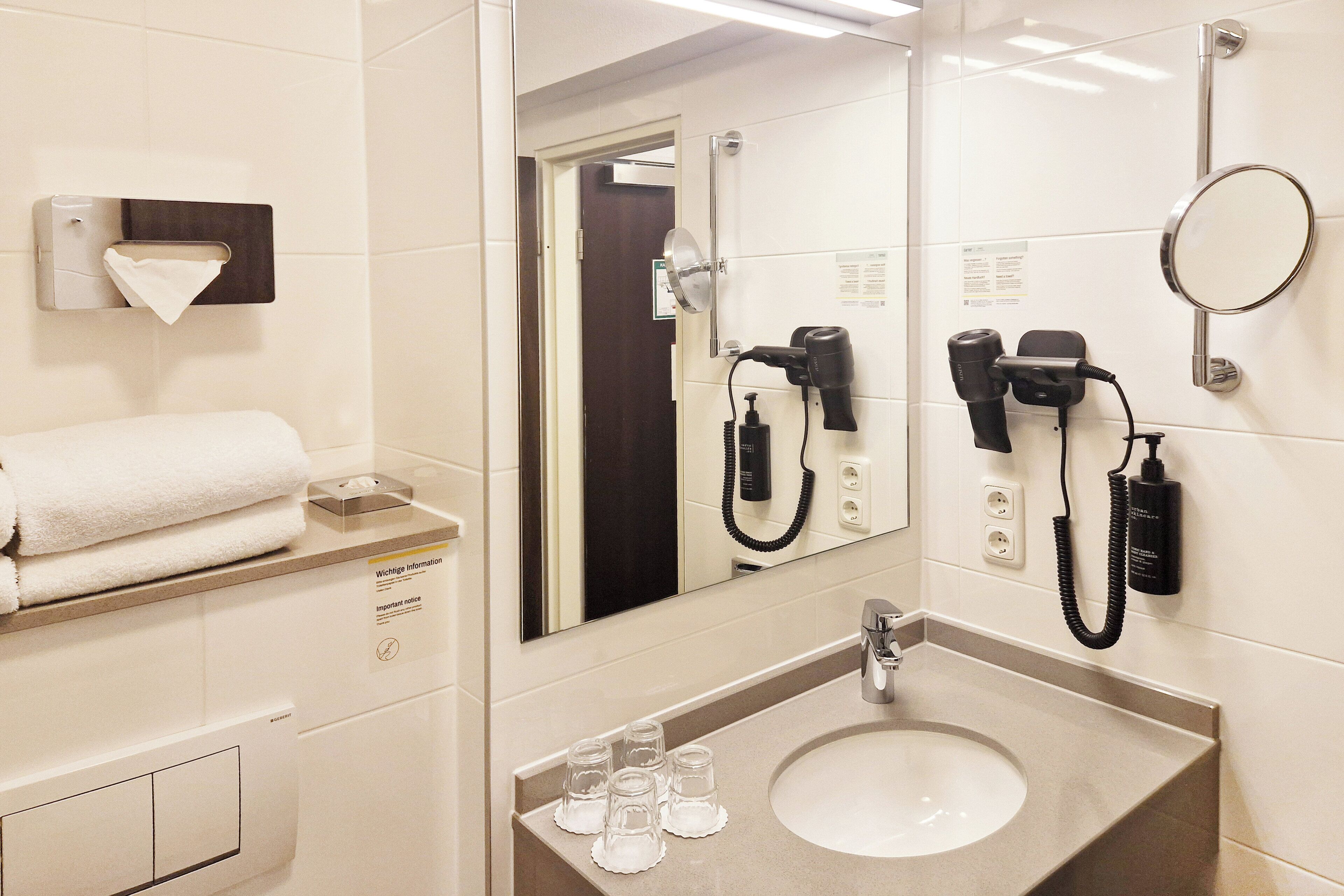 Ein Badezimmer mit Waschbecken, Spiegel, Handtuchhalter und Fön.