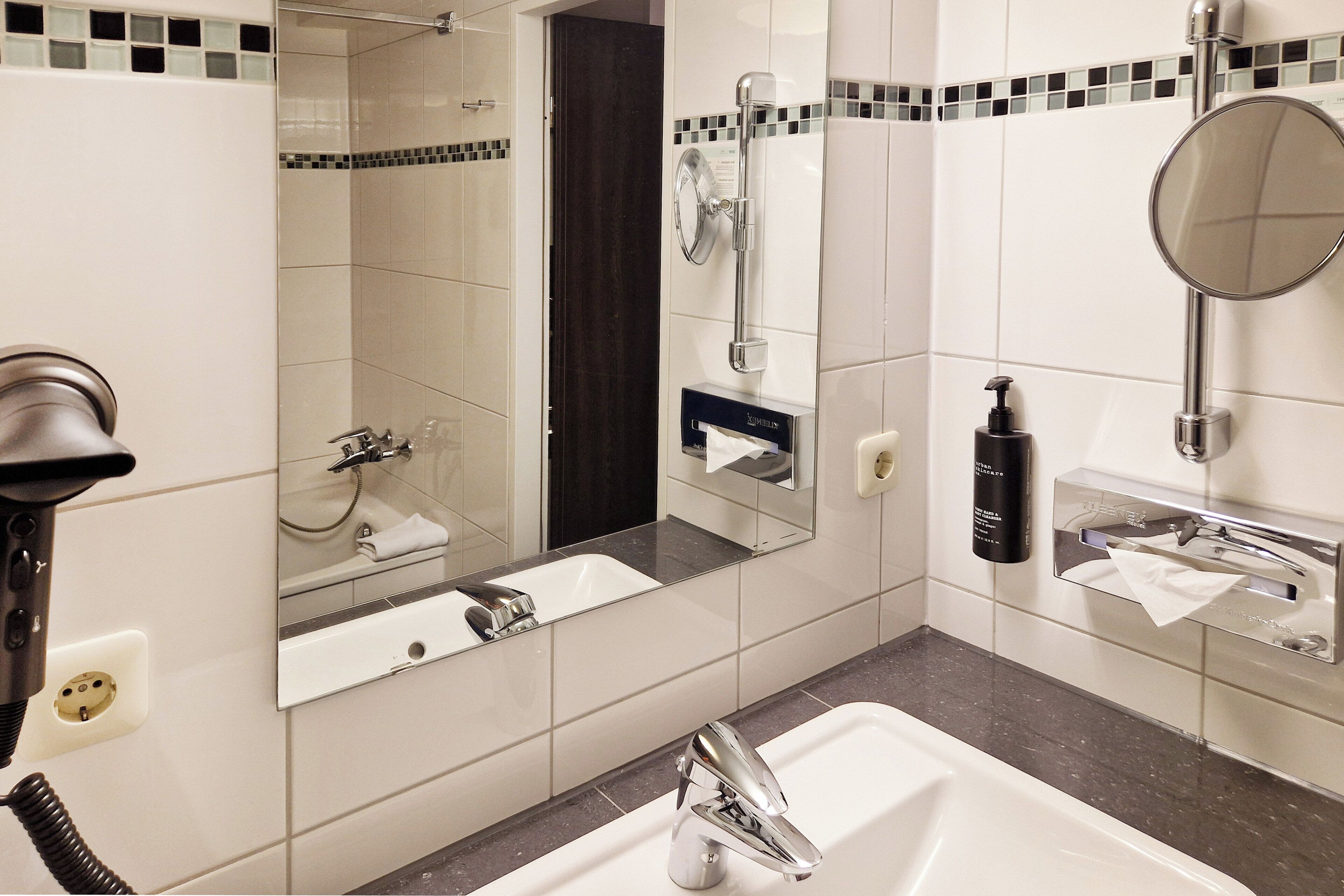 A modern bathroom with a large mirror, a sink, and a shower area.