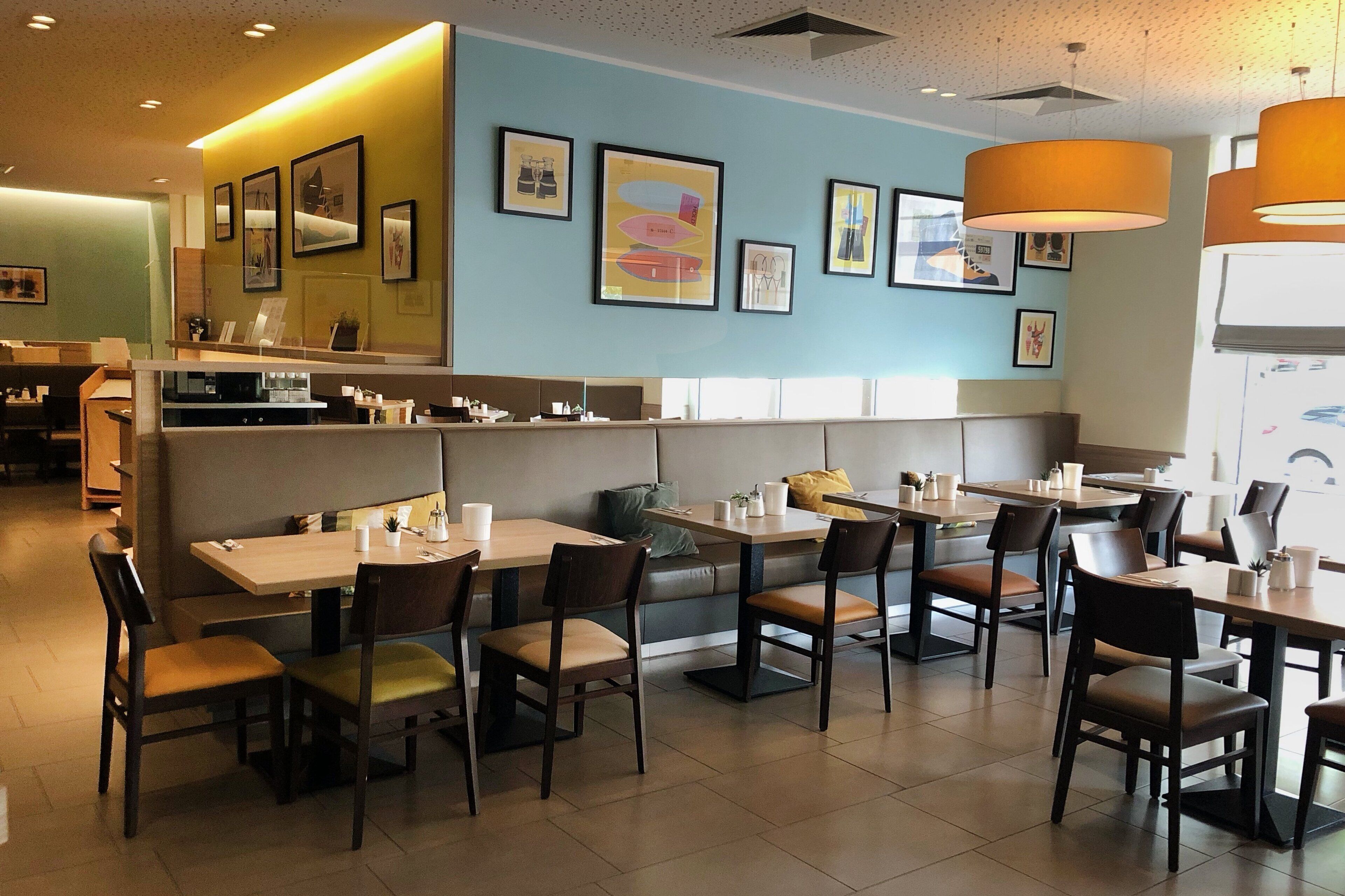 Un restaurant avec des banquettes et des tables, un comptoir et des œuvres d’art accrochées aux murs.
