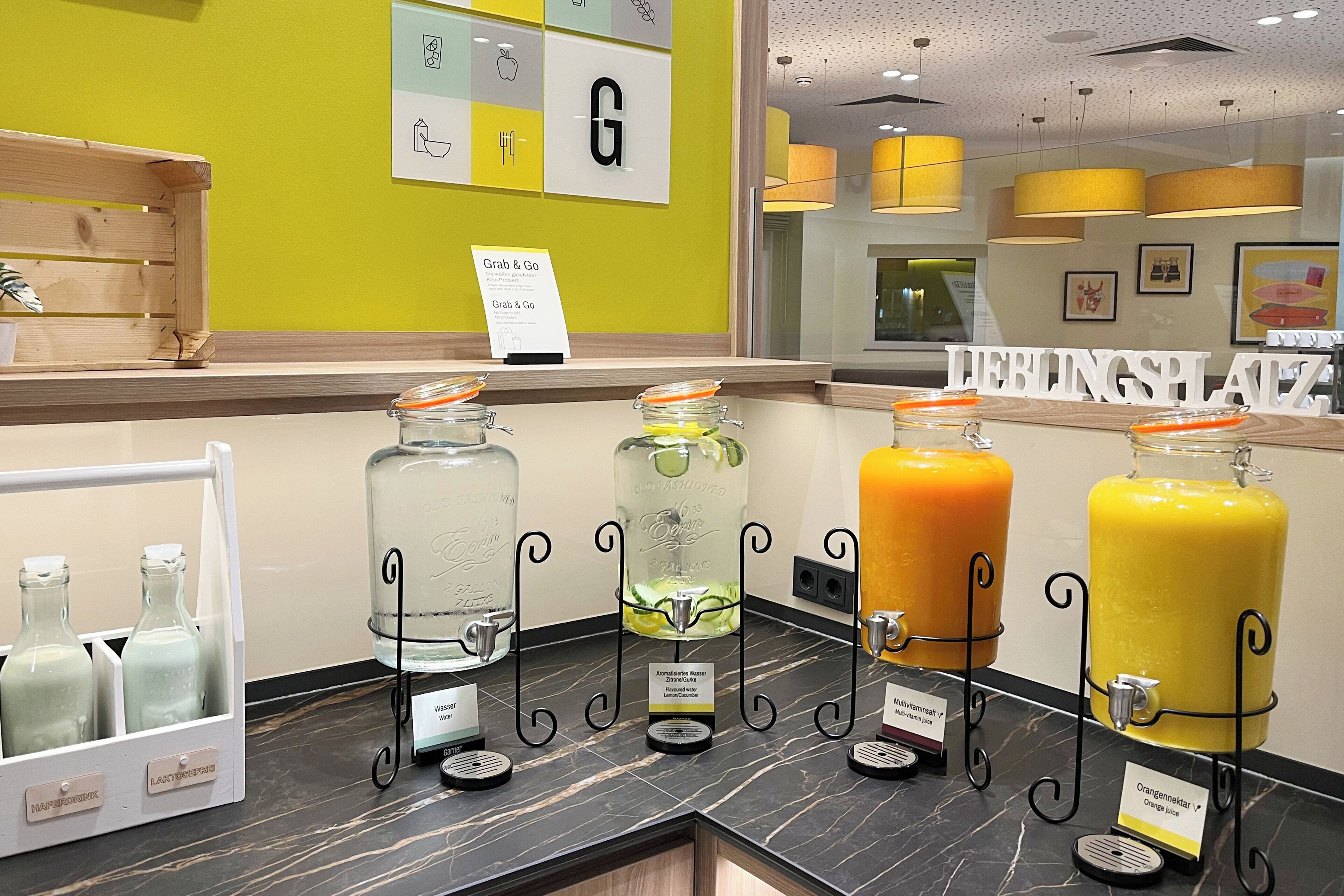 A juice bar with three dispensers labeled 'Lemonade', 'Cucumber', and 'Orange Juice'.