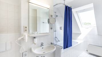A modern bathroom with a white sink, mirror, and shower.