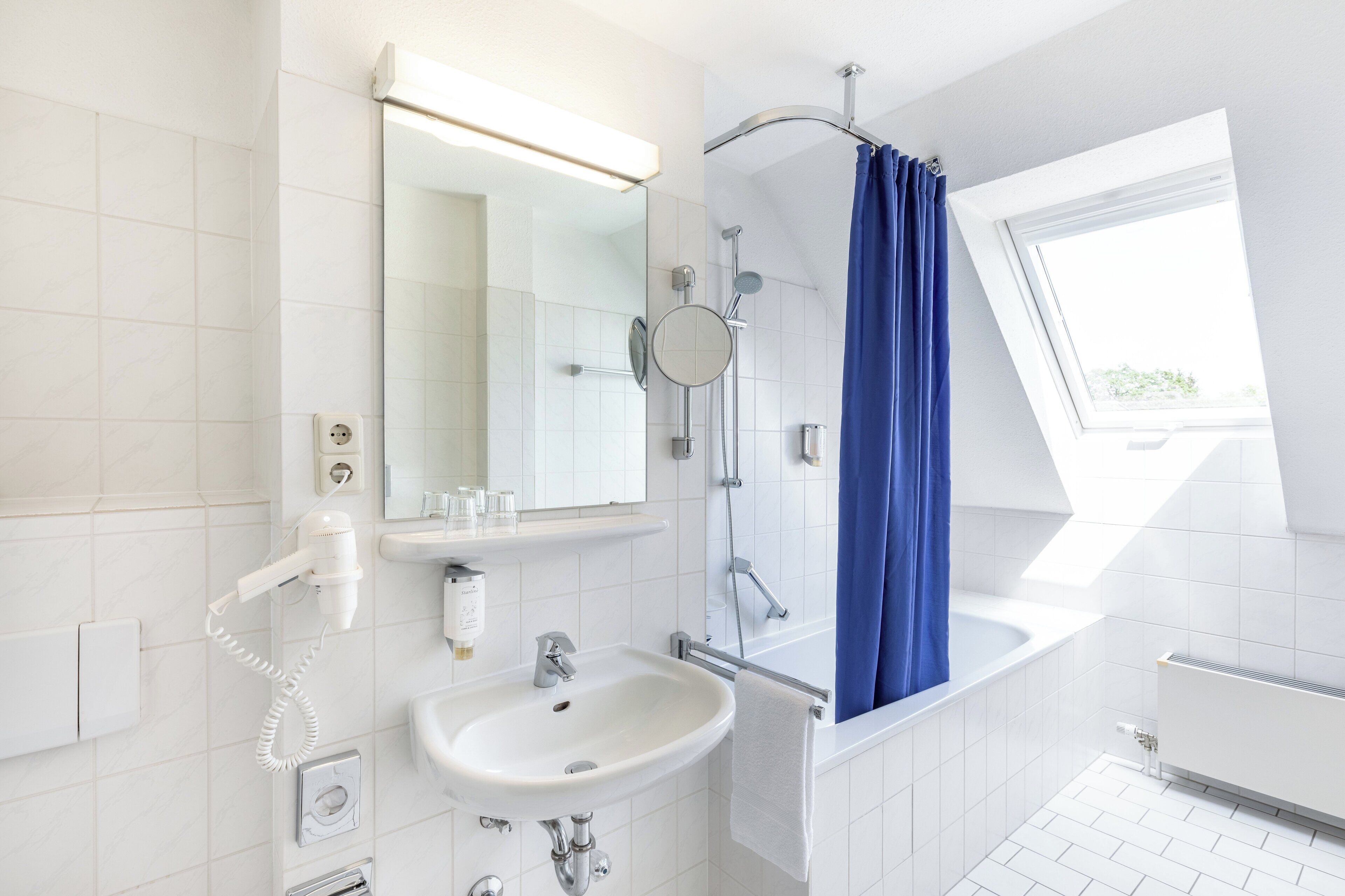 A modern bathroom with a white sink, mirror, and shower.