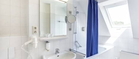A modern bathroom with a white sink, mirror, and shower.