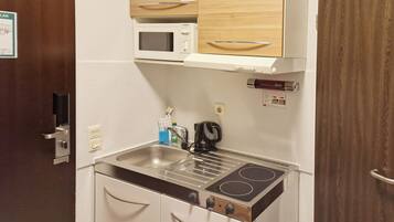 A compact kitchenette with a microwave, stove, and sink.